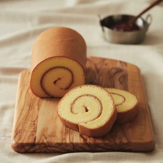 Bolu gulung dengan lapisan krim dan hiasan gula halus